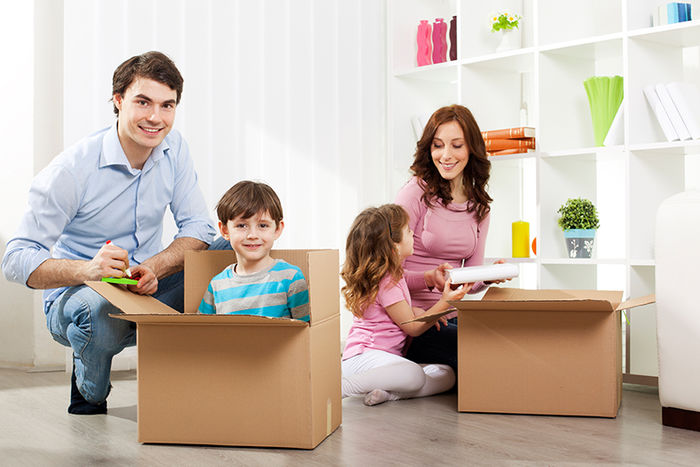 Ein junge Familie packt Kisten aus.