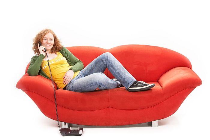 Das Foto zeigt eine junge Frau auf einem Sofa beim Telefonieren. Das Foto ist von der BITel.